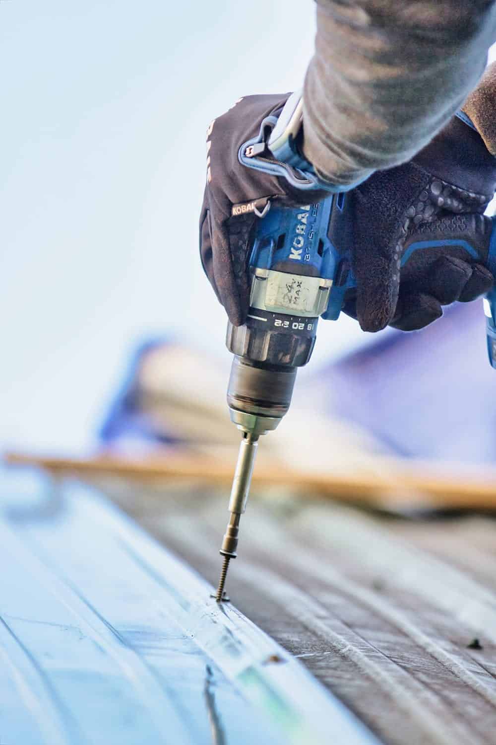 Worker using a Kobalt drill to secure roofing materials, emphasizing Texcore Construction's expertise in roofing installation and repairs.