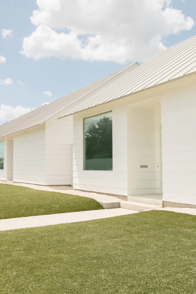 Modern white house in Houston with professional roofing installation and glass windows