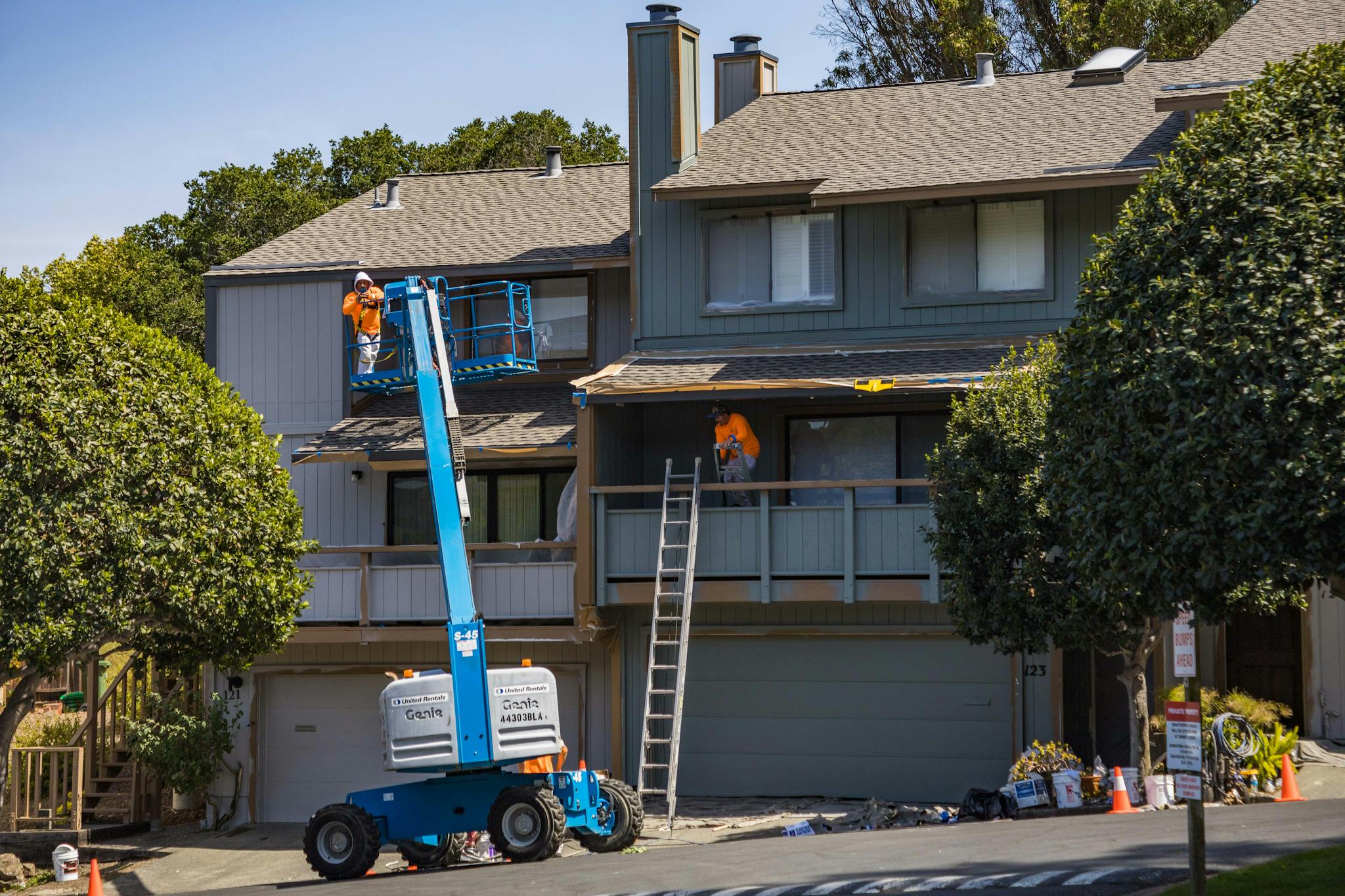 Workers on a lift and ladder performing roofing renovations on a residential building, showcasing Texcore Construction's commercial roofing services in Fort Worth, Texas.